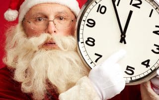 Santa pointing at a large clock.