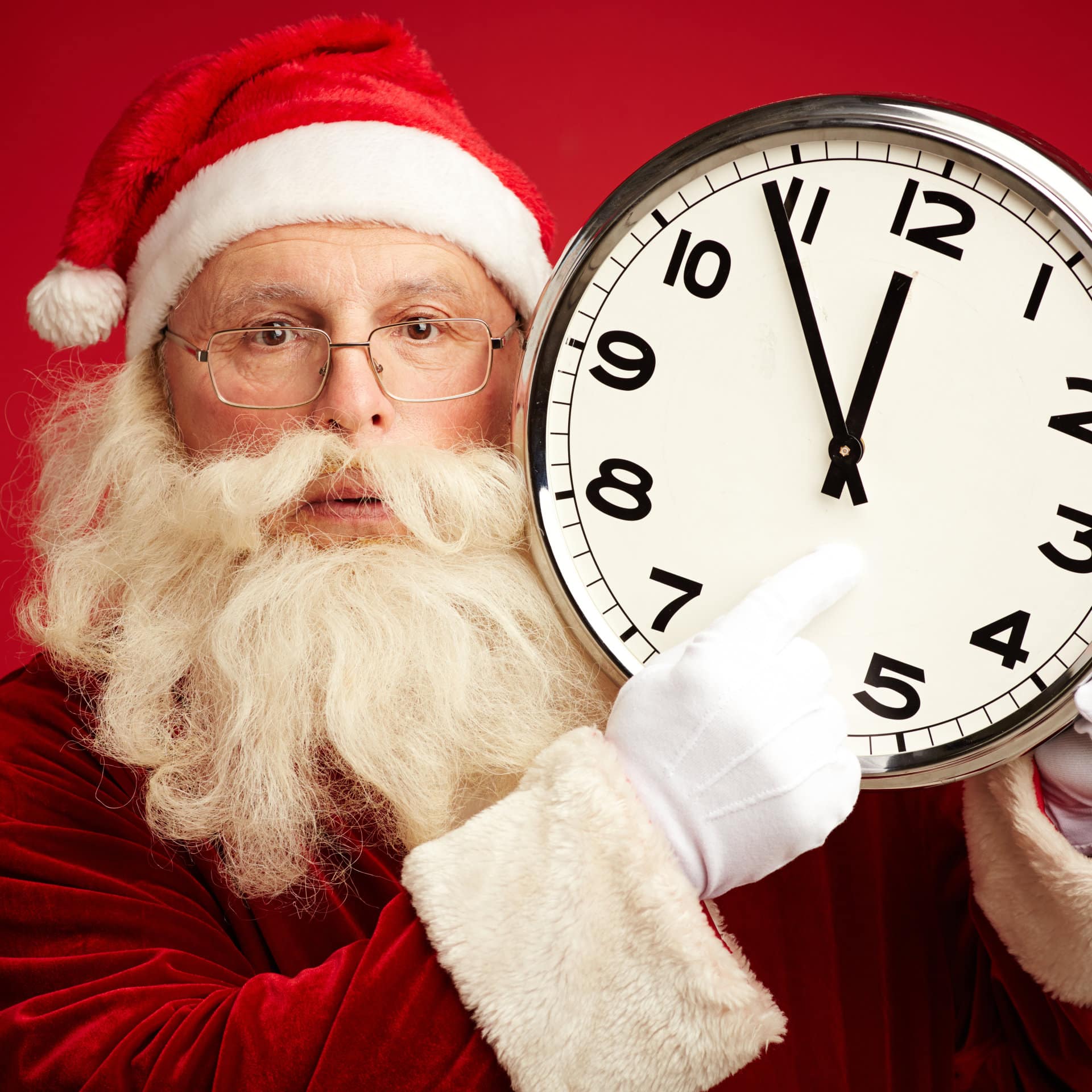Santa pointing at a large clock.