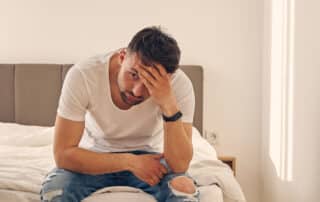 Anxious Caucasian man spending time at home in the bedroom while thinking of his problems.