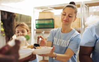 A volunteer serves food to a homeless person, but can it heal a broken society?