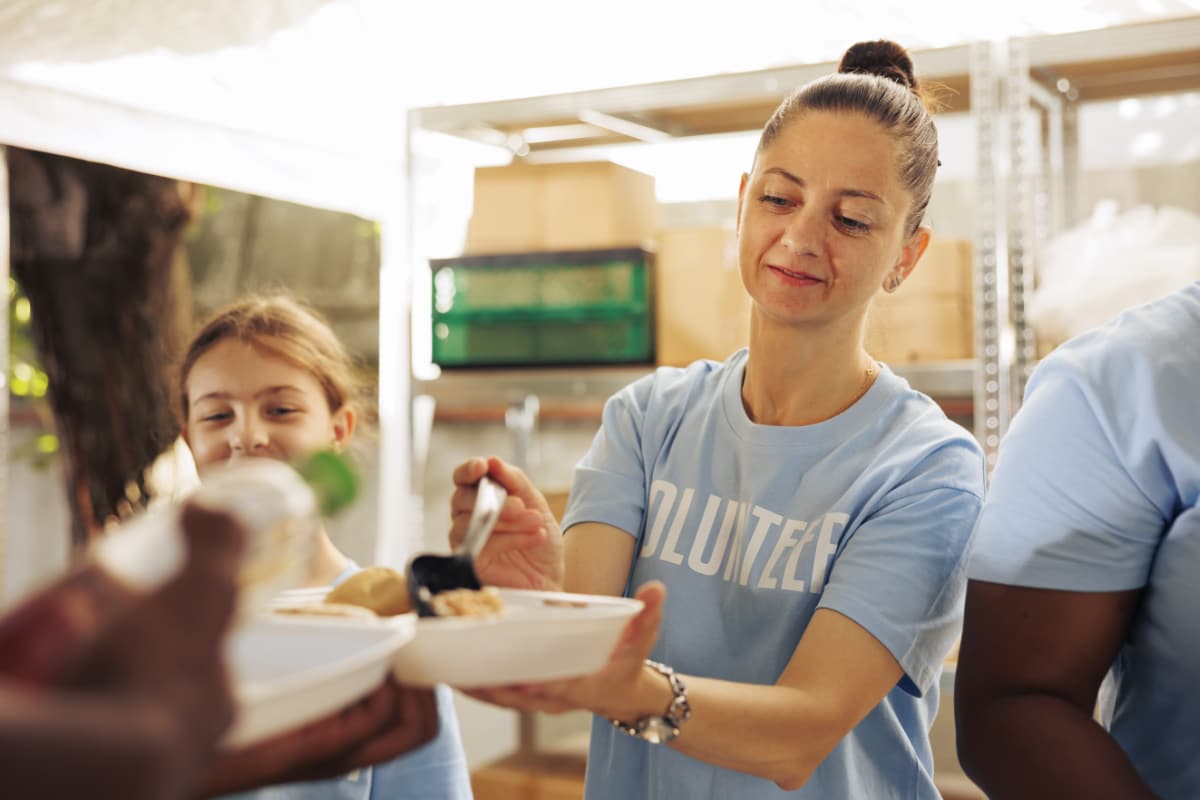 A volunteer serves food to a homeless person, but can it heal a broken society?