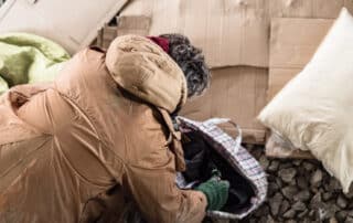 A homeless man arranging his bedding.