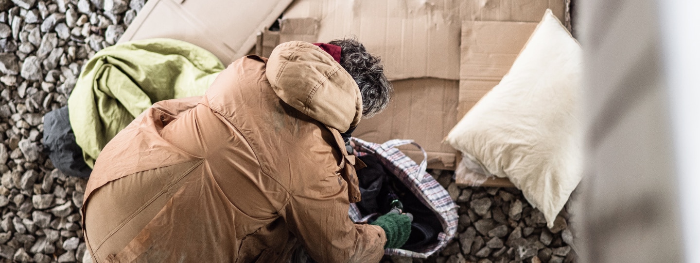 A homeless man arranging his bedding.