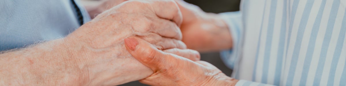 An elderly couple's hands in an embrace.